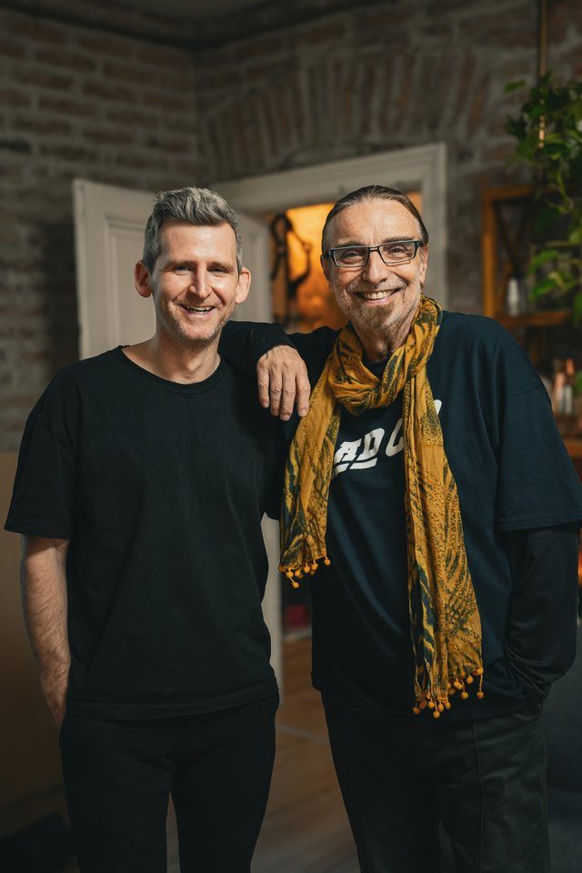 Michael Plank mit einem Gast mit Brille und gelbem Schal